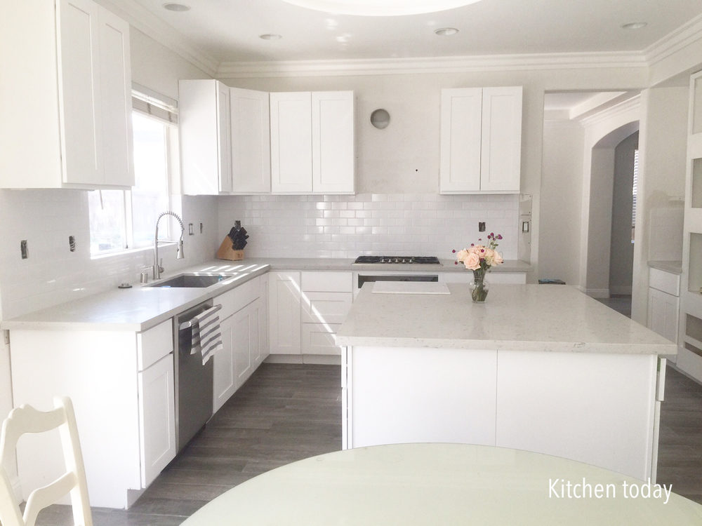 White shaker cabinets (still missing pulls & glass doors) with light gray quartz countertop