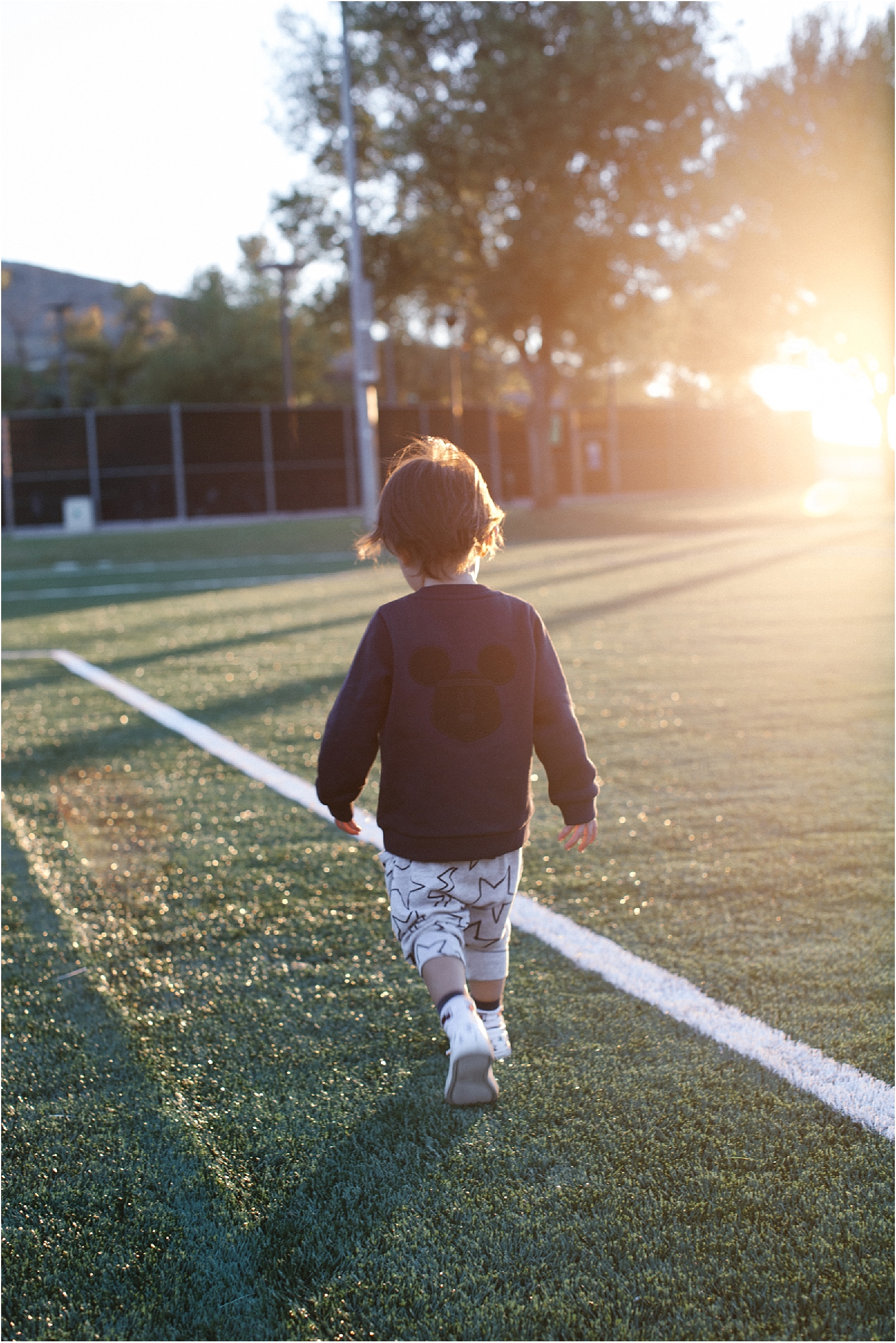 little boy in the field during sunset